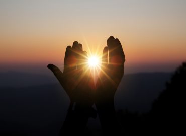 Faith of christian concept: Spiritual prayer hands over sun shine with blurred beautiful sunset background